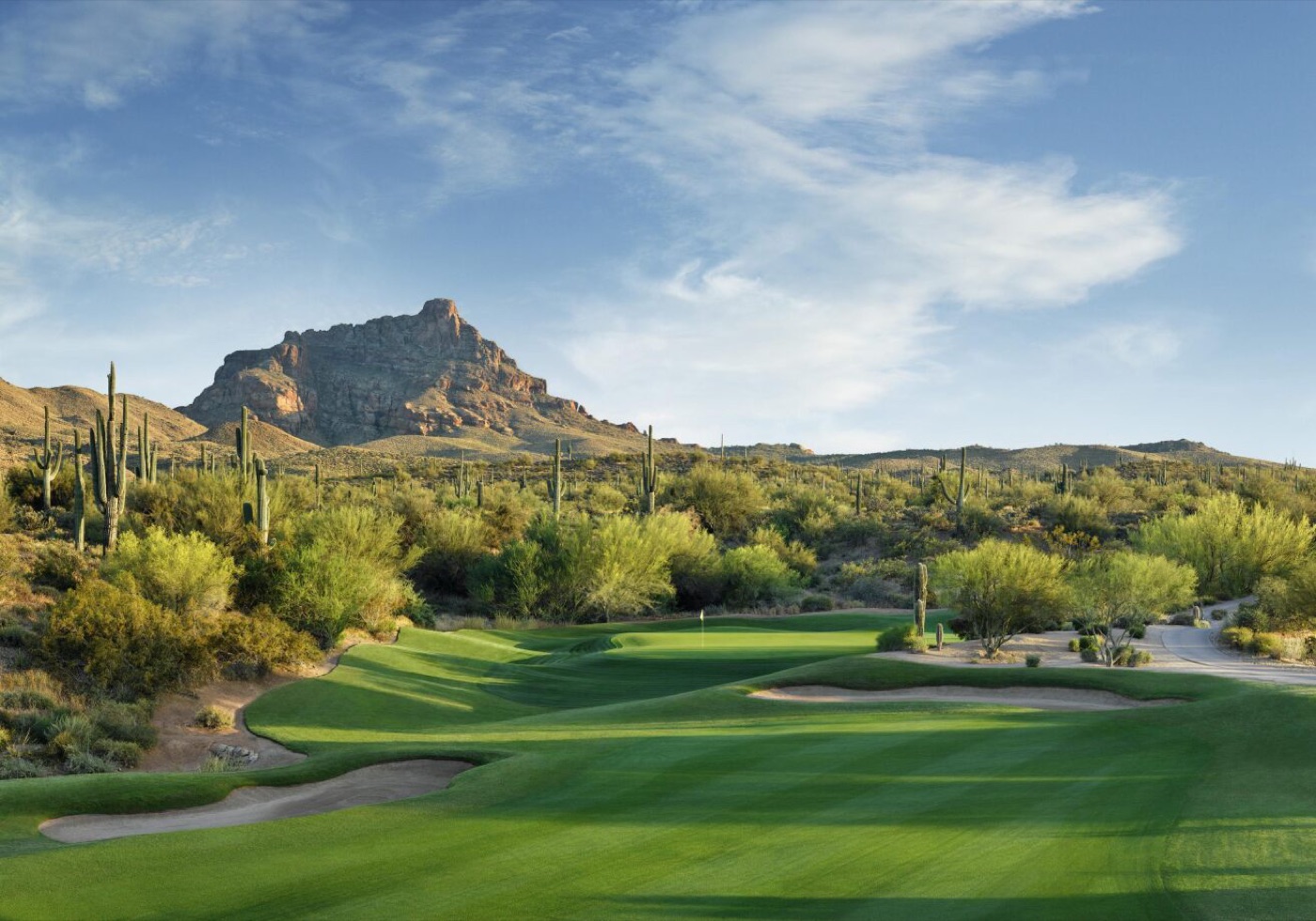 A desert golf hole framed by saguaro cacti and a craggy mountain in Scottsdale, Arizona